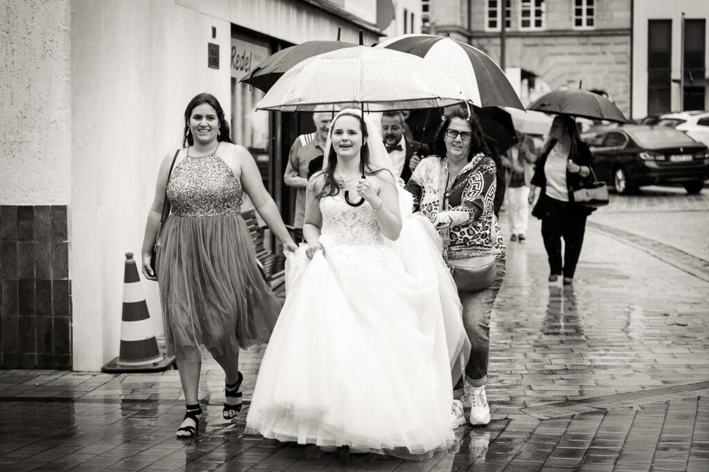 braut und gaeste laufen mit schirmen