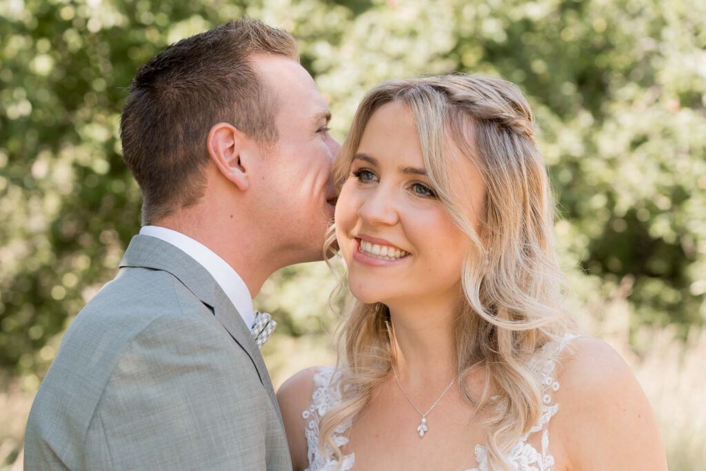 braeutigam fluestert braut ins ohr brautpaarshooting